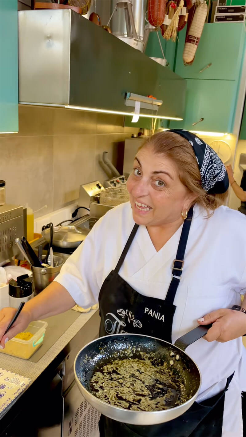 Chef Rania holding a pan and smiling.